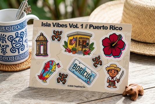 A 6x4 inch "Isla Vibes Vol. 1" sticker sheet featuring 9 Puerto Rican themed vinyl stickers including a Casita, Garita, El Jibarito, and Flor de Maga. The sheet is displayed on a rustic wooden table next to a traditional white and blue ceramic mug and a straw pava hat. Created by TROPIDRIP CO.
