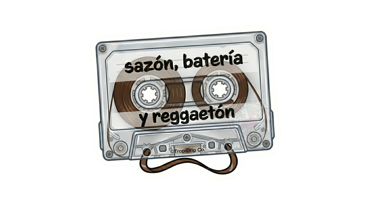 A nostalgic retro-style vinyl sticker shaped like a clear plastic audio cassette tape. The words 'sazón, batería y reggaeton' are printed across the center in a casual, bold black lowercase font. The detailed illustration shows the inner gears, transparent housing, and a realistic loop of brown magnetic tape spilling out from the bottom center. The entire design is outlined with a clean white die-cut border featuring a small '©TropiDrip Co.' brand tag.