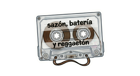 A nostalgic retro-style vinyl sticker shaped like a clear plastic audio cassette tape. The words 'sazón, batería y reggaeton' are printed across the center in a casual, bold black lowercase font. The detailed illustration shows the inner gears, transparent housing, and a realistic loop of brown magnetic tape spilling out from the bottom center. The entire design is outlined with a clean white die-cut border featuring a small '©TropiDrip Co.' brand tag.